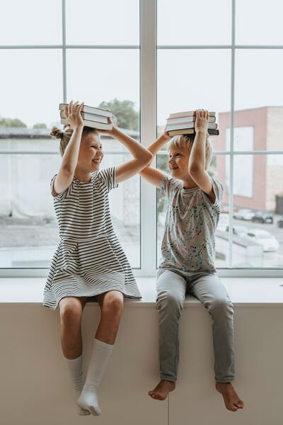 Twee kinderen houden een stapel boeken boven hun hoofd