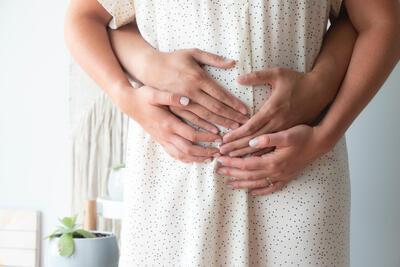 Handen van man en vrouw op zwangere buik