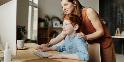 Moeder helpt zoon aan de computer